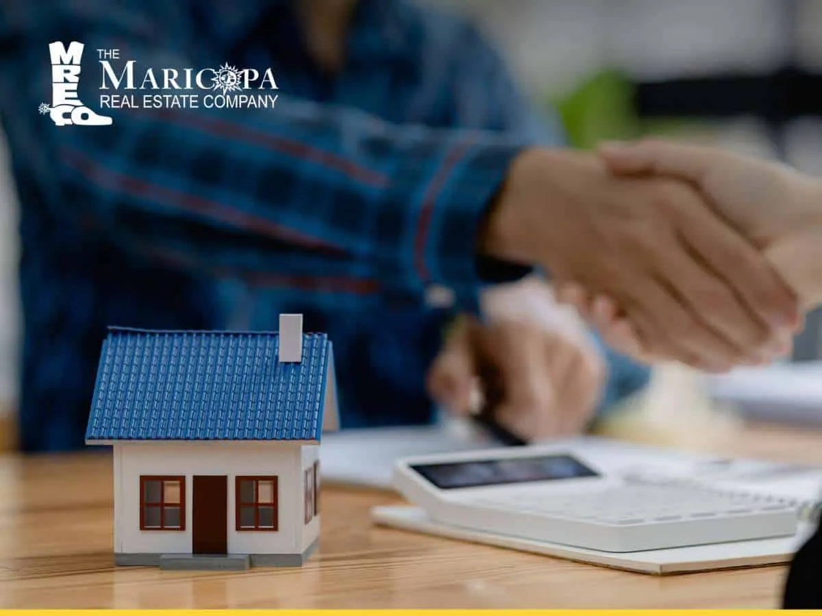 Handshake over paperwork and model home, symbolizing buying a house in Arizona